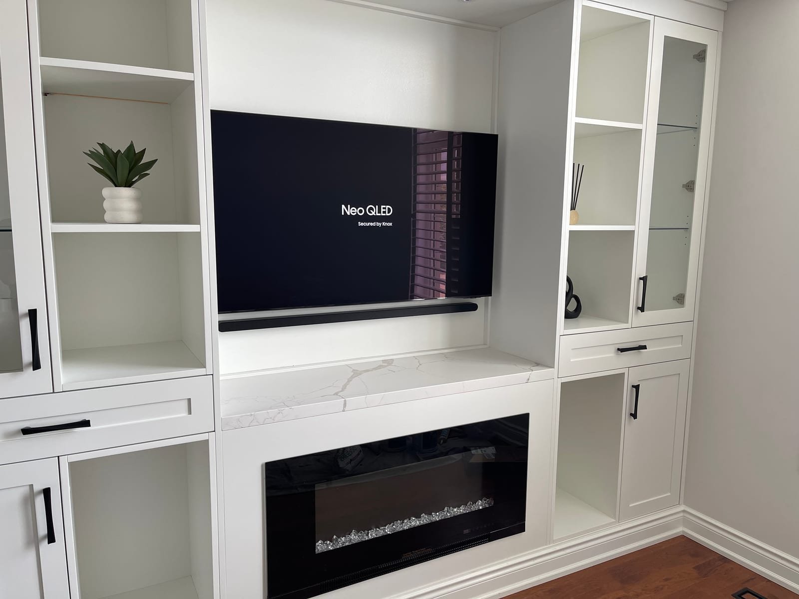 Wall-mounted television and soundbar installed in a custom built-in fireplace wall